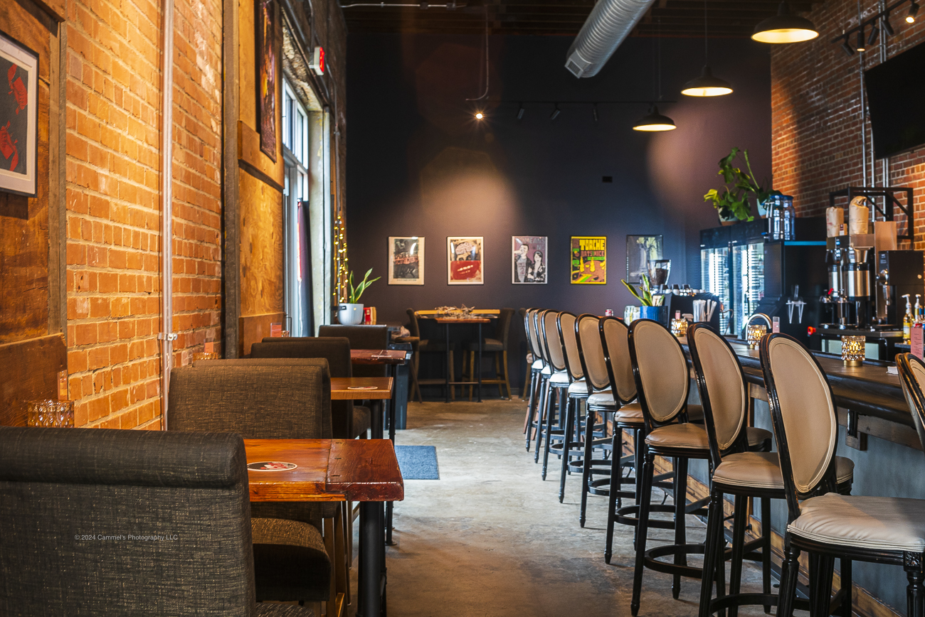 Bar stools lined along the counter beside brick walls and framed art
