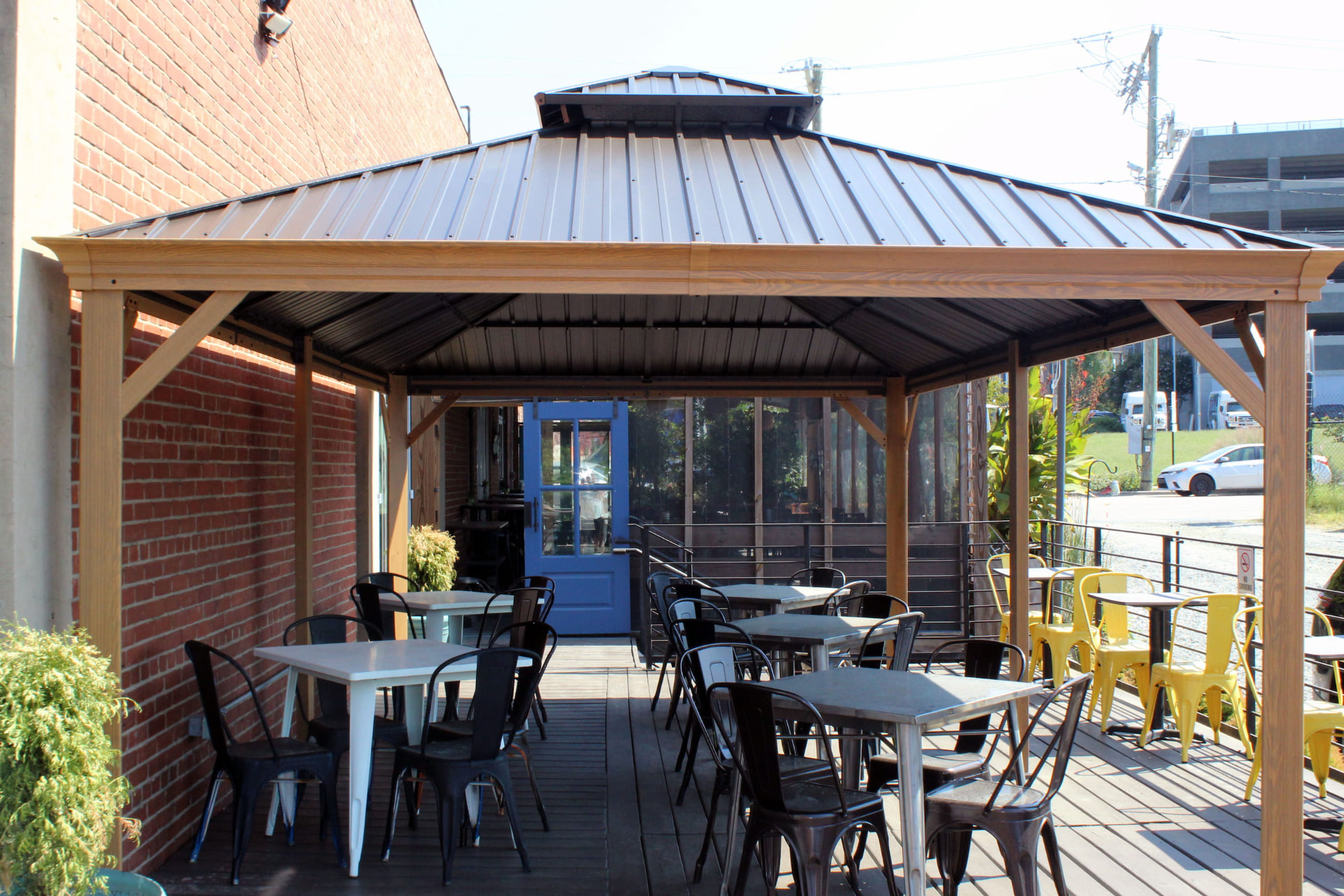 Covered outdoor patio with wooden pergola, tables and a blue door at Prophecy Social House
