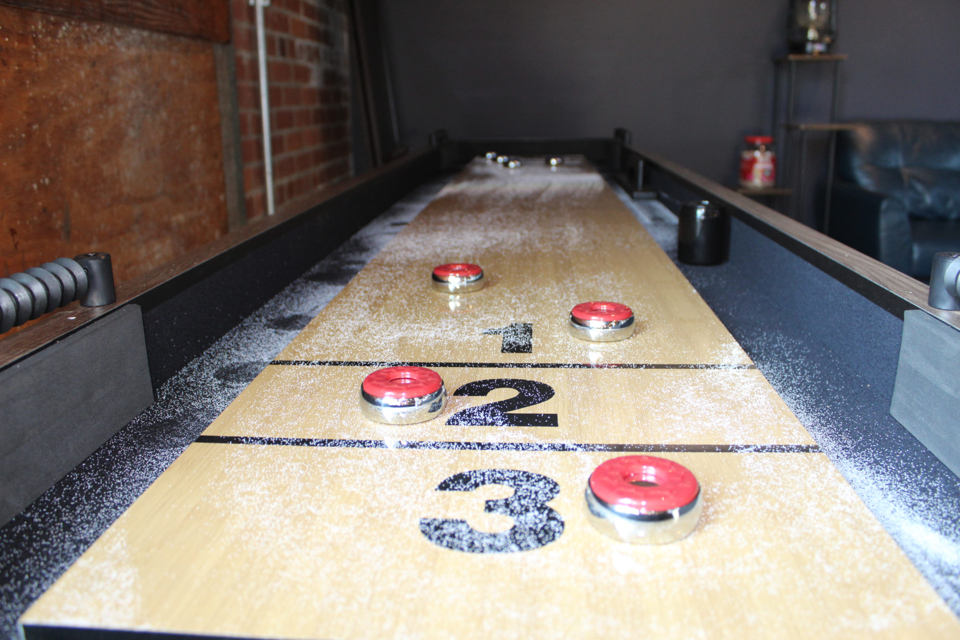 Shuffleboard table with red pucks at Prophecy Social House